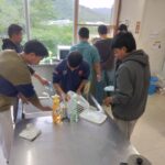 電子コンロ自体とその周辺の油汚れを清掃する実習生。