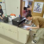 電子コンロ自体とその周辺の油汚れを清掃する実習生。
